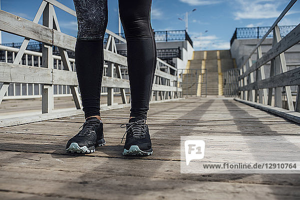 Legs of athletic woman standing on a pier