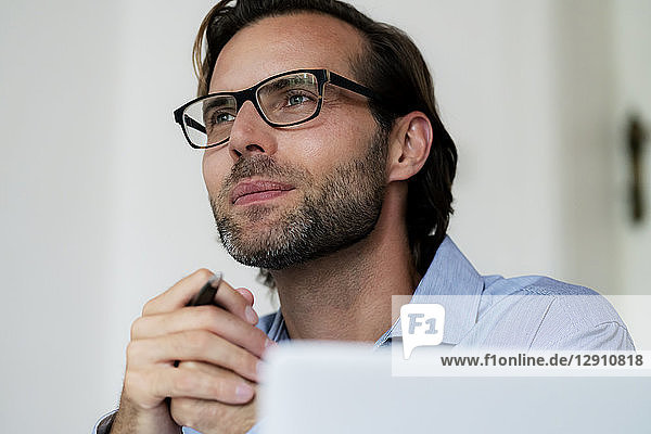 Smiling businessman wearing glasses and holding pen