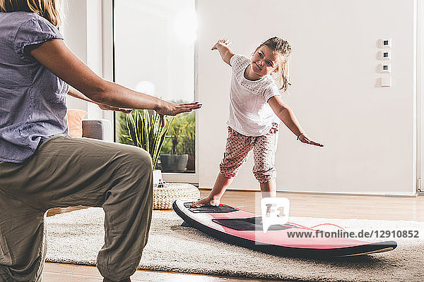 Mother and daughter exercising with surfboard in living room