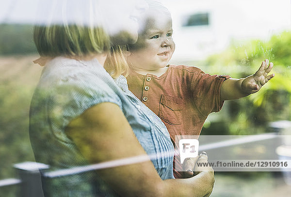 Mother looking out of window  with son on her arm