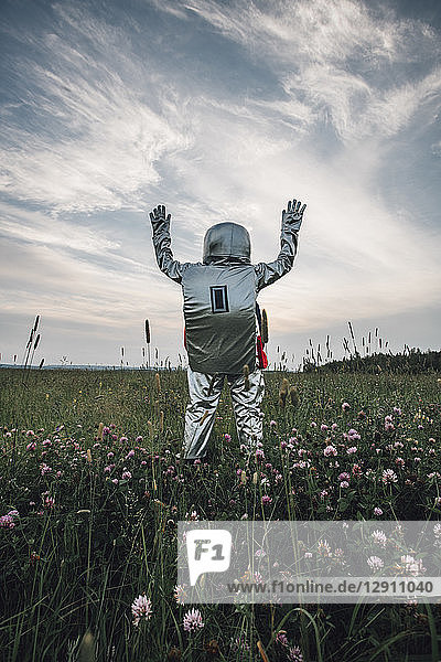 Spaceman exploring nature  standing in meadow  waving