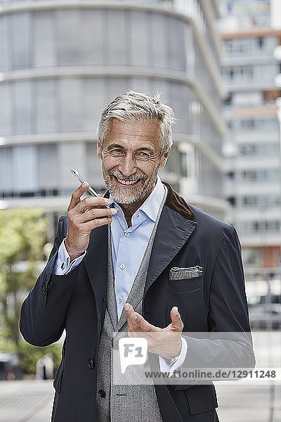 Germany  Duesseldorf  portrait of laughing mature businessman talking on mobile phone