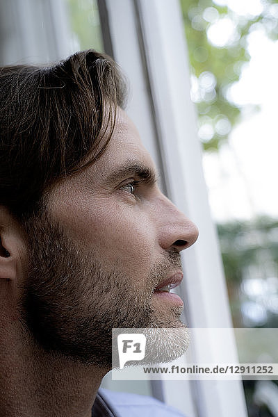 Close-up of man looking out of window