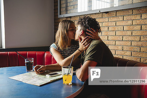 Young couple with map kissing in a cafe