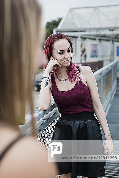 Smiling young woman with dyed hair standing on footbridge