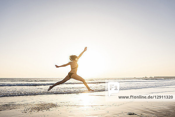 Young woman jumping for joy on the beach