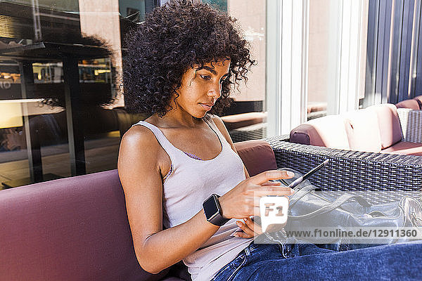 Portrait of young woman sitting at sidewalk cafe using digital tablet