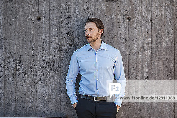Portrait of businessman standing at concrete wall