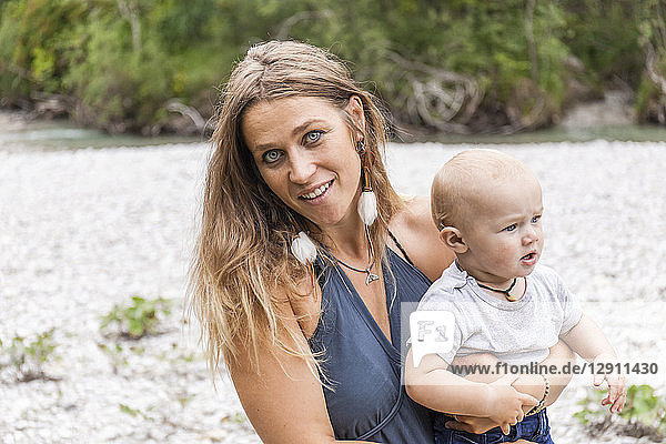 Portrait of smiling mother holding baby boy outdoors in nature