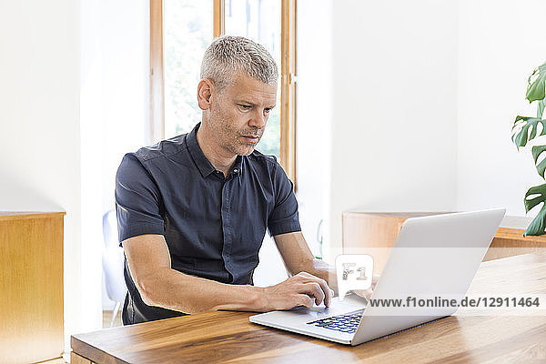 Mature man using laptop on wooden table
