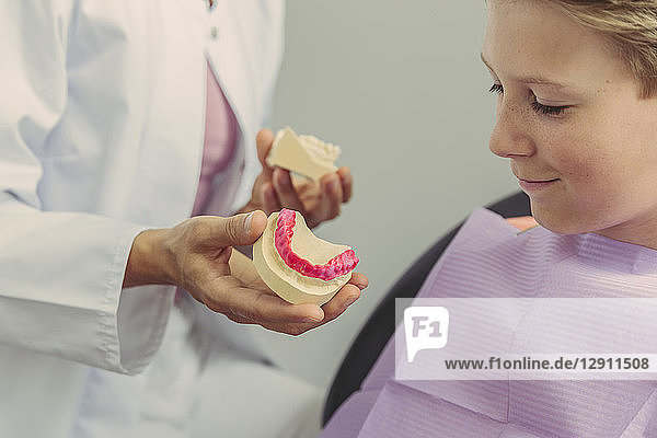 Female dentist explaining boy a tooth model