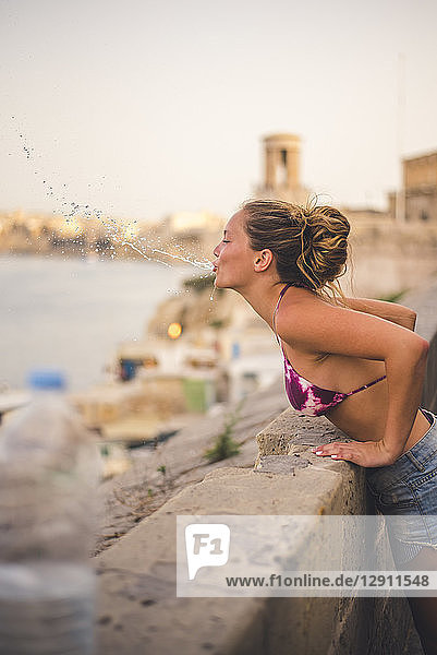 Malta  Valletta  Teenage girl spitting water over wall
