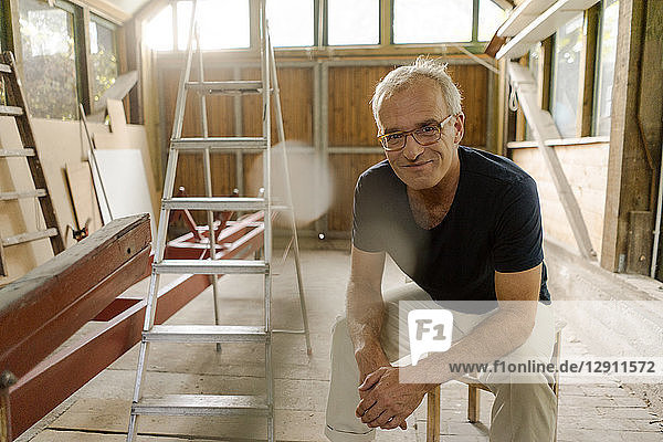 Portrait of a confident mature man sitting in his workshop