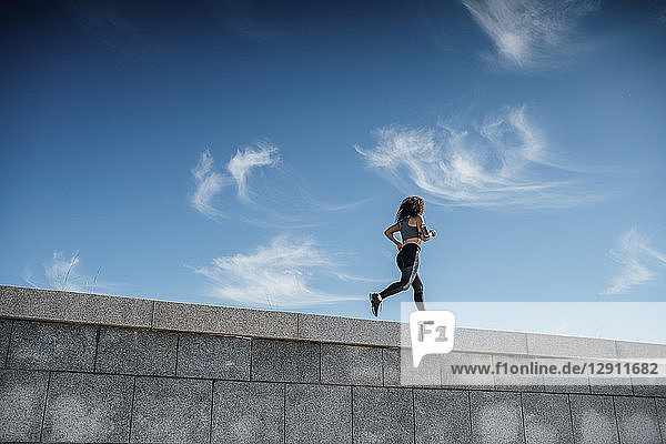 Young athletic woman running on a wall
