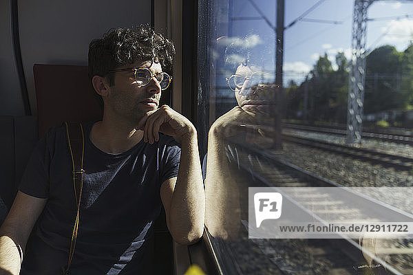 Man traveling by train looking out of window