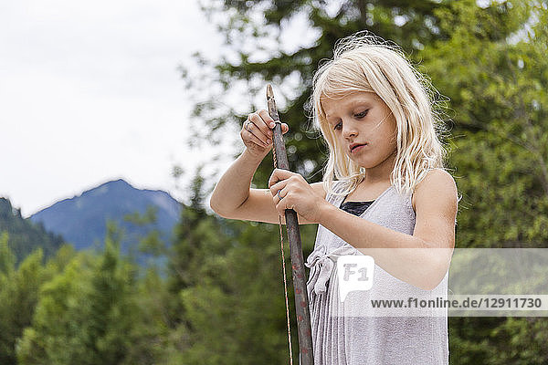 Girl holding a selfmade bow outdoors