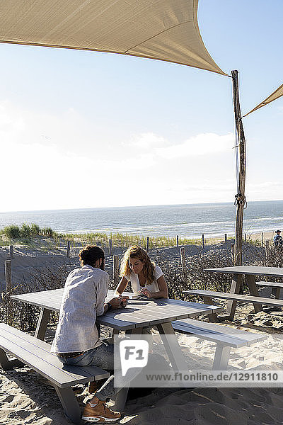 Young couple using digital tablet  sitting a ta a table at the beach