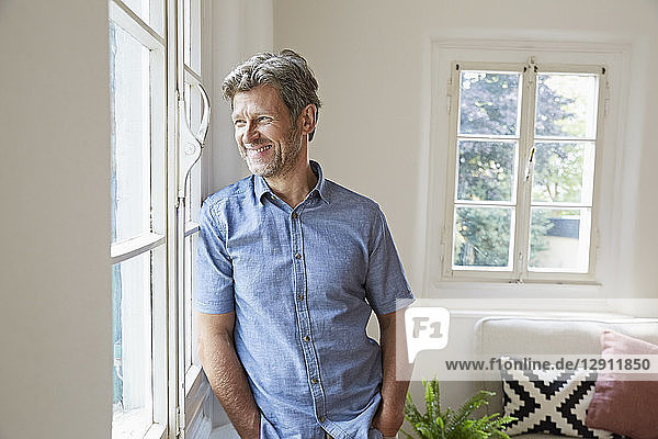 Mature man at home eaning at window