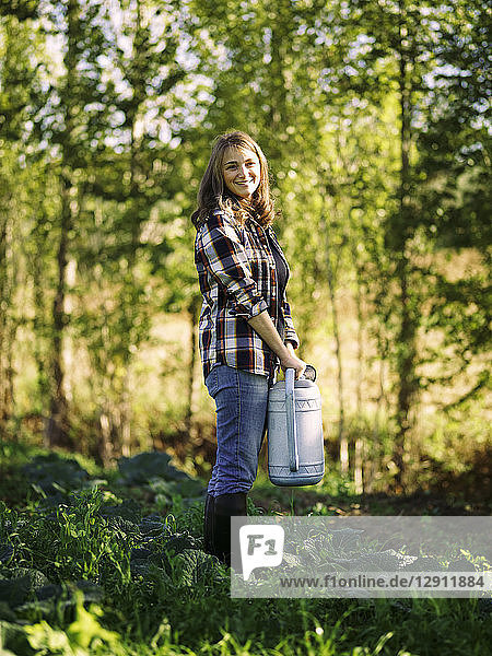 Portrait of smiling farmer with watering can on a field