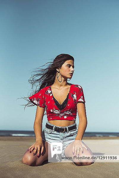 Fashionable teenage girl sitting on the beach