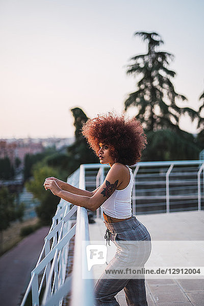 Portrait of pensive young woman on terrace at evening twilight