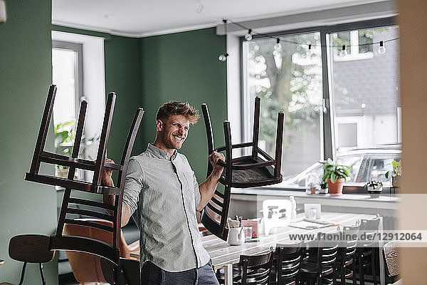 Young business owner lifting chairs