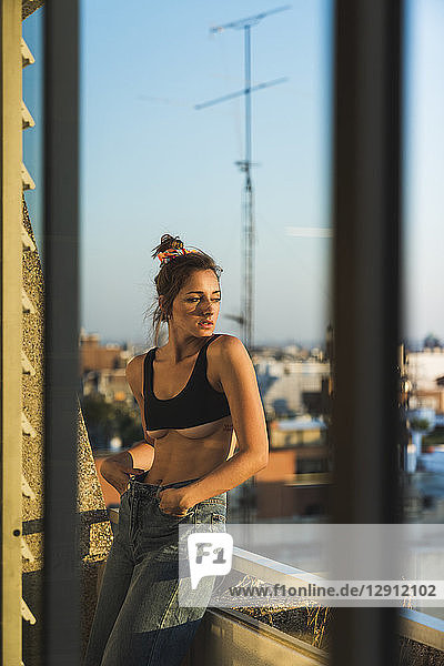Young woman wearing bra standing on balcony