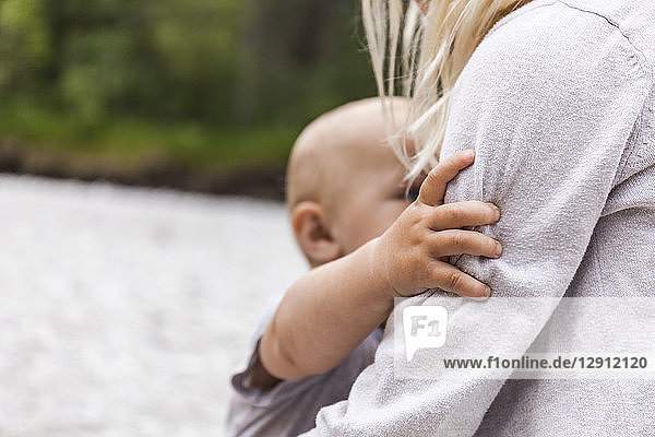 Girl holding baby boy brother in the nature
