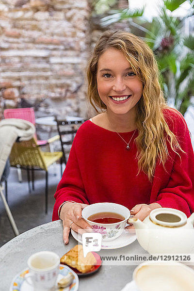 Portrait of smiling young woman with tea cup at pavement cafe