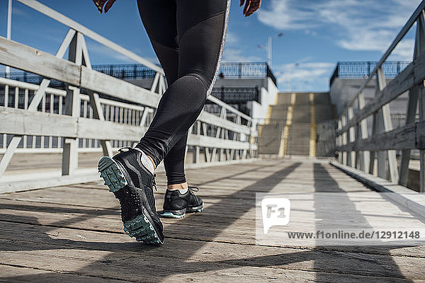 Legs of athletic woman running on a pier