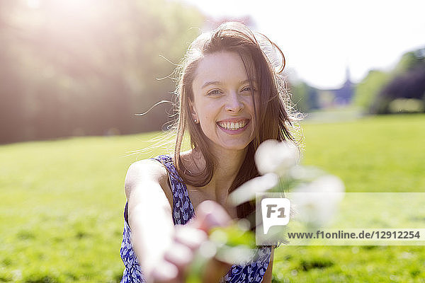 Portrait of smiling young woman in a park holding flowers