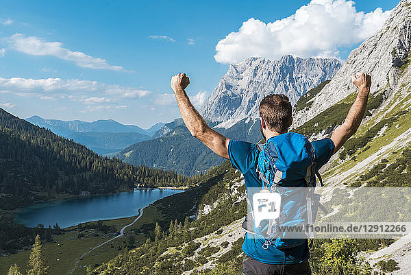 Austria  Tyrol  Hiker with backpack  raising arms  looking at Lake Seebensee