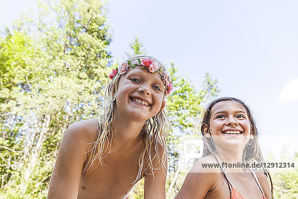 Portrait of happy girl wearing flower crown and friend outdoors in summer
