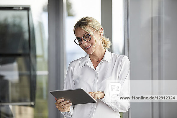 Businesswoman leaning on window  using digital tablet
