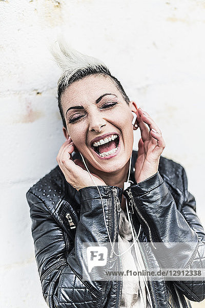 Exuberant punk woman listening to music with earbuds