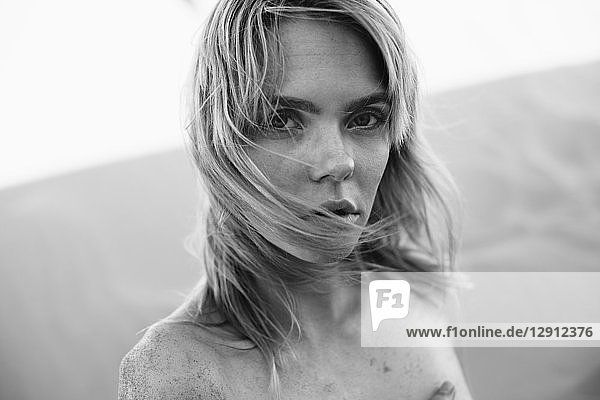 Black and white portrait of a beautiful young woman covered with sand