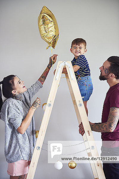 Modern family decorating the home at Christmas time using ladder as Christmas tree