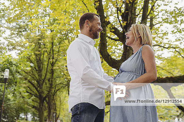 Happy mature pregnant couple talking in park