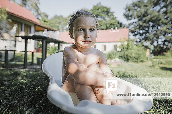Portrait of little girl sitting in bath tub in garden