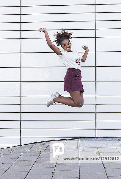 Portrait of laughing young woman jumping in the air