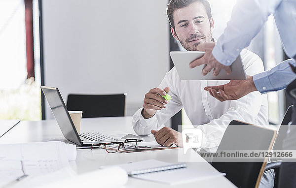 Businessman sharing tablet with colleague in office