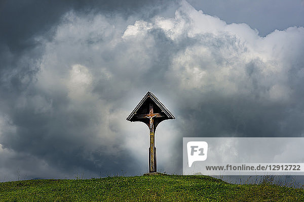 Germany  Bavaria  Allgaeu  Allgaeu Alps  wayside cross with Jesus figurine in front of dramatic sky