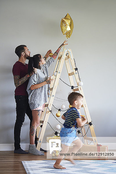 Modern family decorating the home at Christmas time using ladder as Christmas tree