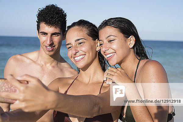 Happy friends taking selfies on the beach