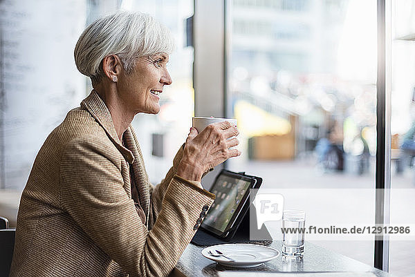 Smiling senior businesswoman with tablet in a cafe