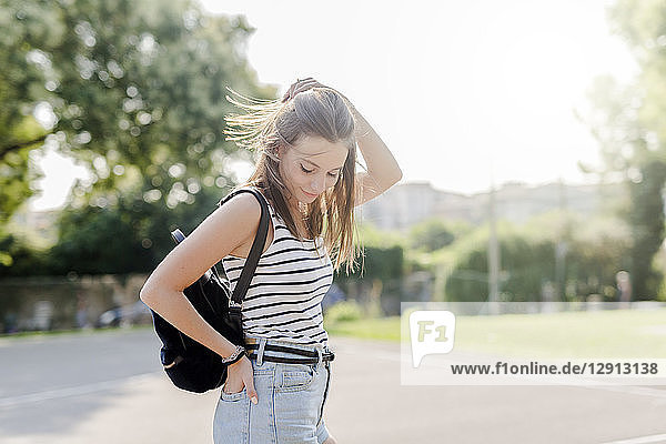 Portrait of smiling young woman with backpack outdoors in summer