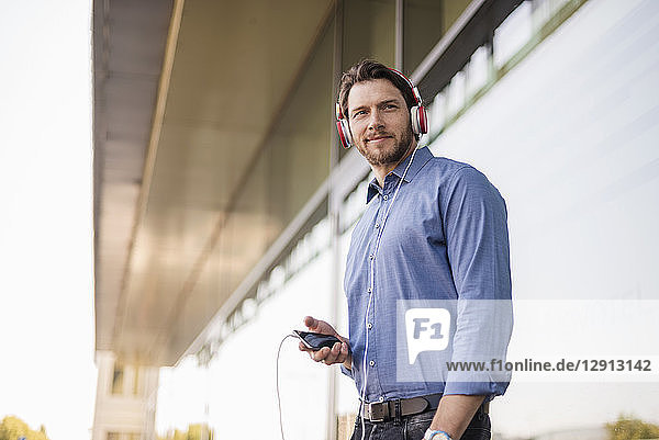 Smiling man listening to music with headphones outdoors