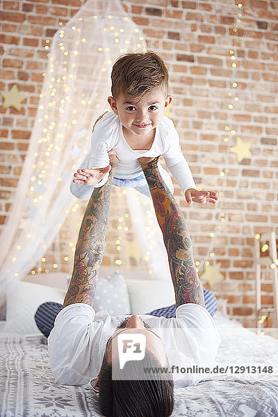 Father lifting up son at Christmas time in bed