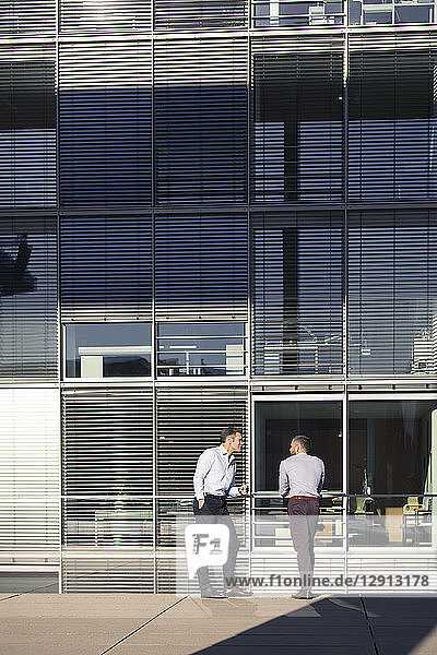 Two businessmen talking outside office building