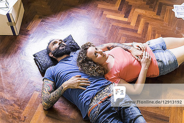 Daydreaming couple lying on the floor of new home